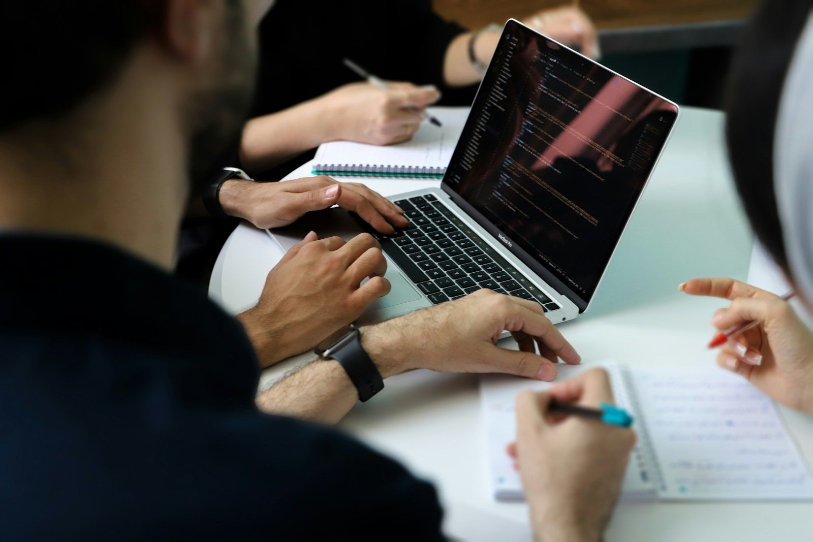 Un gruppo di persone al lavoro attorno a un computer portatile