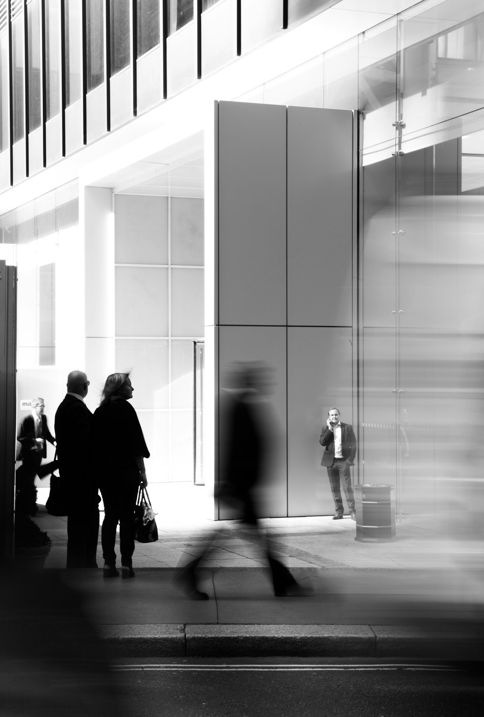 Foto in scala di grigi di persone che camminano verso un edificio
